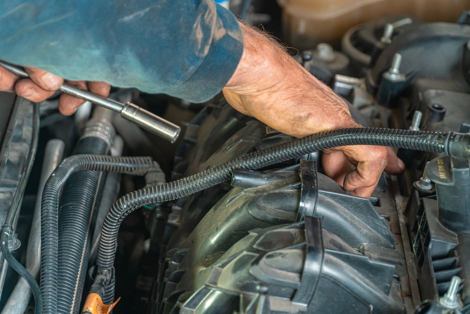 Technik servisu Klimafix pri plnení klimatizácie pod otvorenou kapotou vozidla